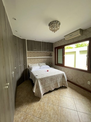 A bedroom with a bed, wardrobe, and a window. - Casa Palmer (Cabo Frio)