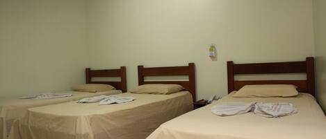 Two single beds with wooden headboards in a room with plain walls and a wooden ceiling.