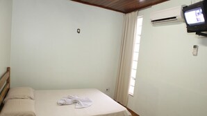 A simple, clean room with a bed, a TV mounted on the wall, and an air conditioning unit. - Tibiriçá Hotel LTDA (Maraba)