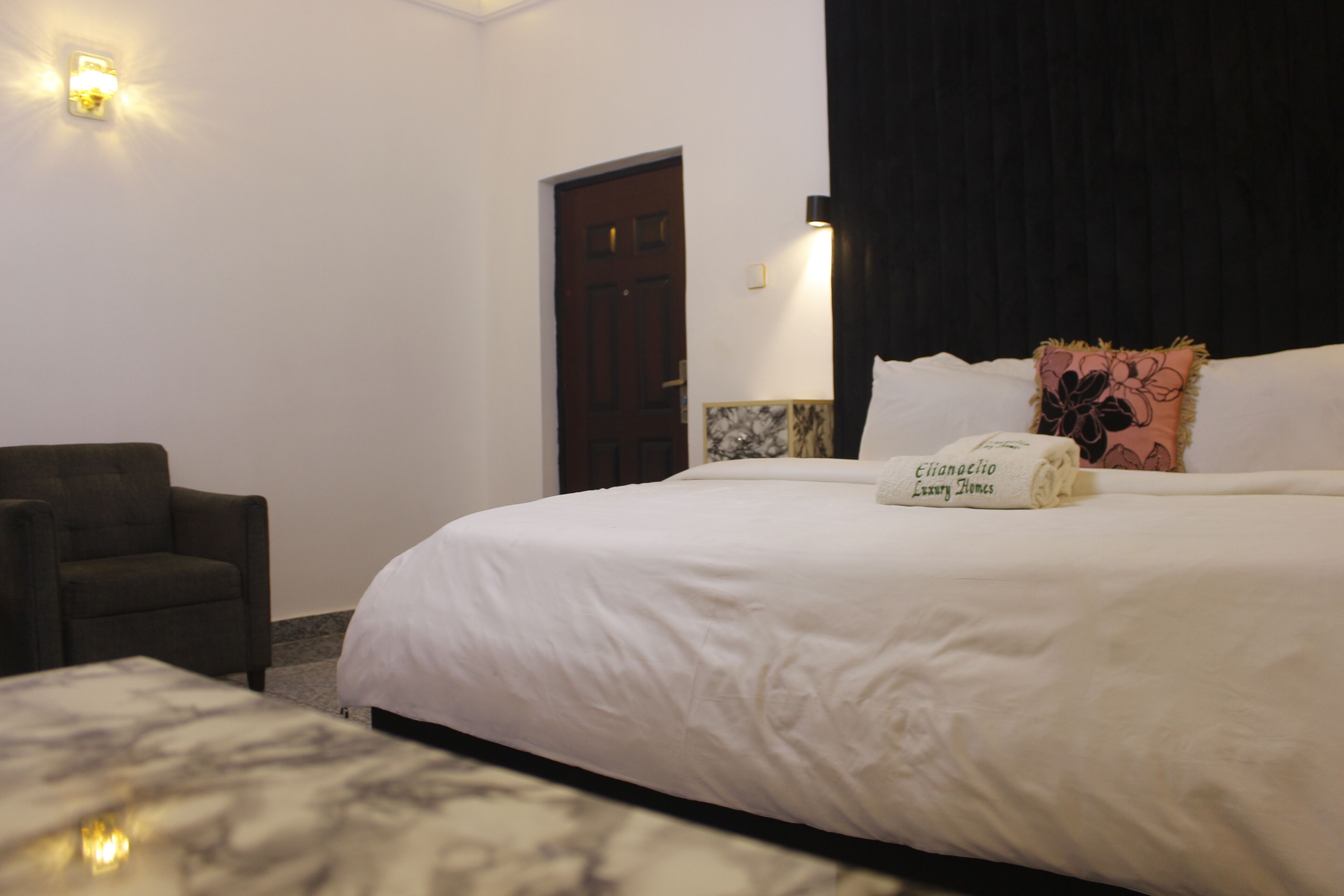 Una habitación de hotel con una cama, una silla y una mesita de noche.