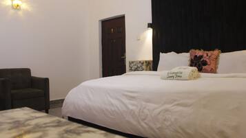 Una habitación de hotel con una cama, una silla y una mesita de noche.