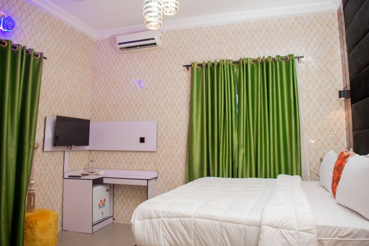 A bedroom with a bed, a desk, and a television.