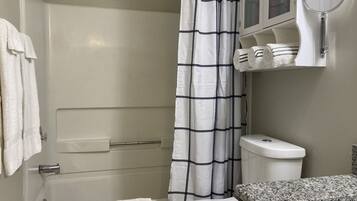 A bathroom with a white bathtub, a white toilet, and a shower curtain with a black grid pattern.