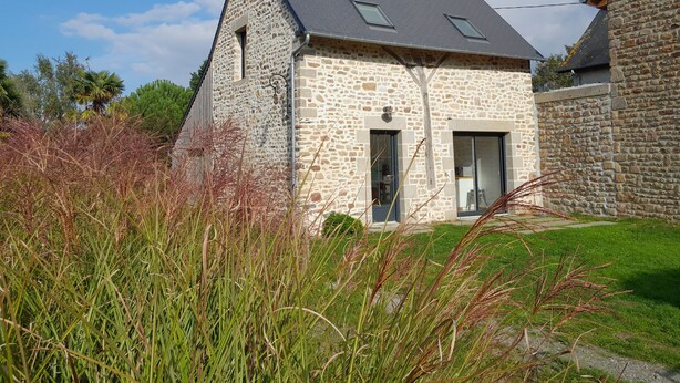 A stone house with a sloped roof, a small porch, and a window. - The House of Strikes... its Dependency (Le Val-Saint-Père)