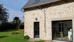 A stone house with a large glass door and a small window. - The House of Strikes... its Dependency (Le Val-Saint-Père)