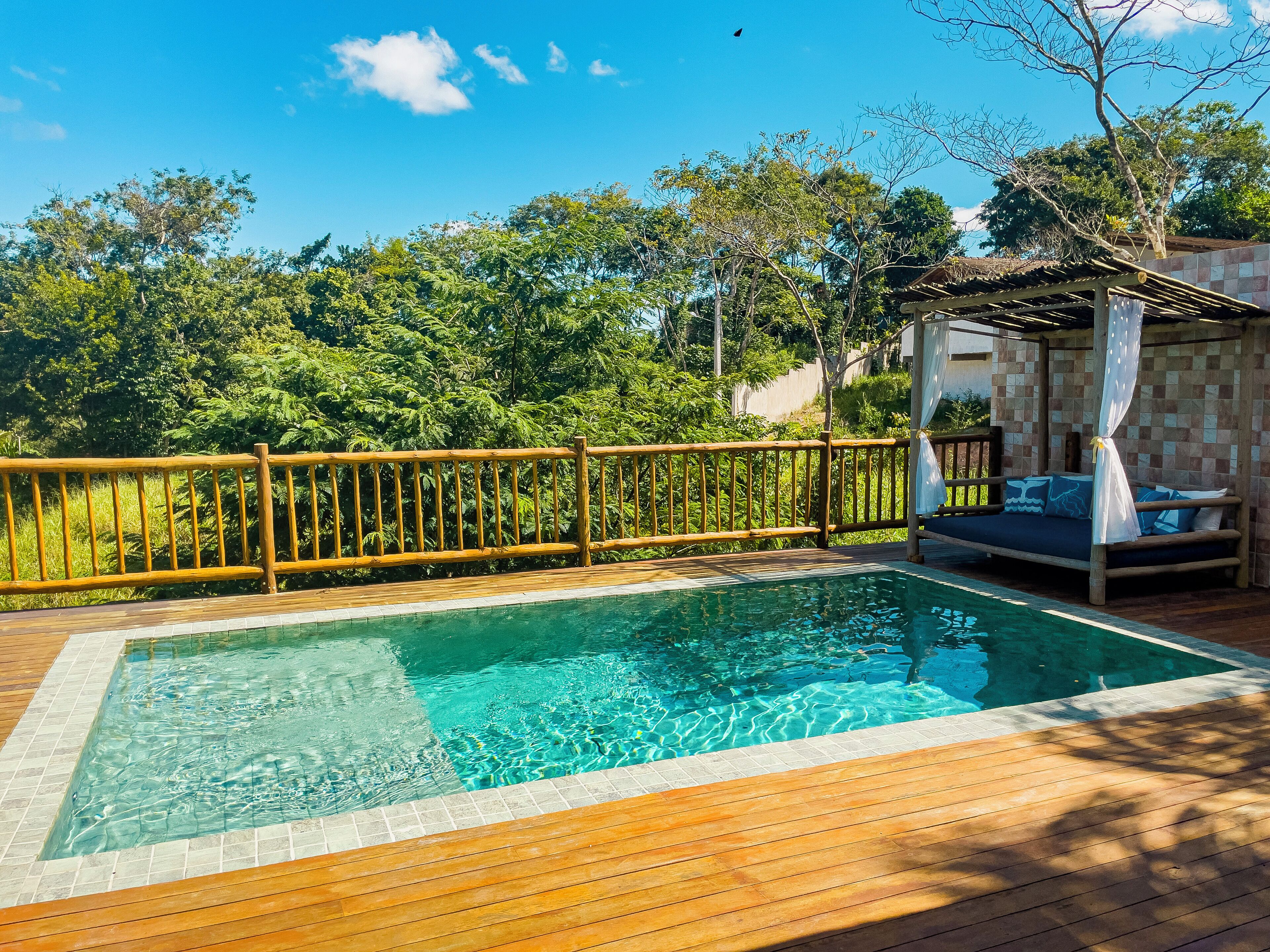 A rectangular pool with clear water, surrounded by a wooden deck and a wooden fence.