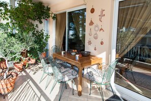 A patio with a wooden table, metal chairs, potted plants, and decorative wall hangings. - Beautiful 3 bedrooms apt in N. Smirni (Nea Smirni)