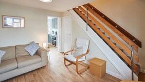 Ein Wohnzimmer mit einer Couch, einem Sessel, einem kleinen Tisch und einer Treppe.