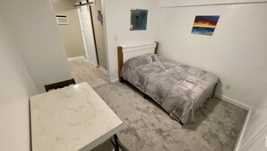 Un dormitorio pequeño con una cama, un escritorio y dos cuadros en la pared.