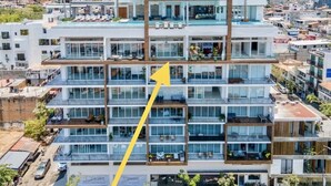 Un hôtel à plusieurs étages, doté de balcons, d’une piscine et offrant une vue sur le paysage urbain environnant.