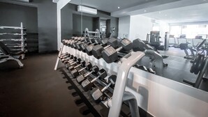 Une salle de sport avec des rangées d’haltères, des appareils d’exercice et un grand miroir.