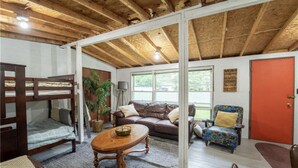 A cozy room with a bunk bed, a sofa, a coffee table, and a chair. - Centrally located spacious cottage just steps from beach and downtown! (Bayfield)