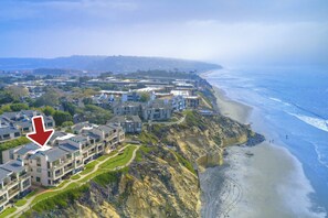 An aerial view of a coastal residential area with modern buildings, a beach, and a cliff. - Oceanfront Fully Remodeled 2BR 2BA | Gated Parking (Solana Beach)
