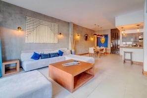 Uma sala moderna com sofá, mesa de centro e área de jantar com cadeiras.
