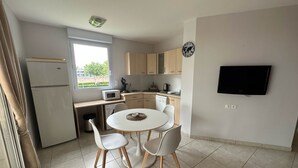 Cocina compacta con comedor, microondas, cafetera y televisión en la pared.