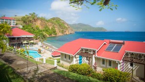 Un complexe hôtelier doté d’une piscine, de bâtiments aux toits rouges et offrant une vue sur l’océan.