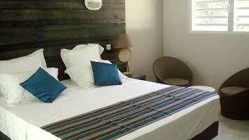 A hotel room with a large bed, a round mirror on the headboard, a lamp, and a chair.