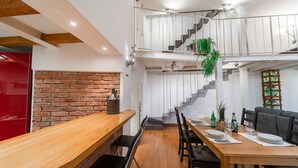 Ein Essbereich mit einem Holztisch, Stühlen und einer Treppe, die zu einer oberen Ebene führt.