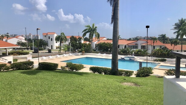 A pool area with a clear blue pool, surrounded by palm trees and a well-maintained lawn. - Villa Ymar Steps to the Pool (Río Grande)