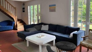 Un salon avec un canapé bleu foncé, une table basse blanche et un escalier.