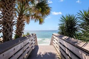 A wooden boardwalk leading to a beach with palm trees and ocean views.
