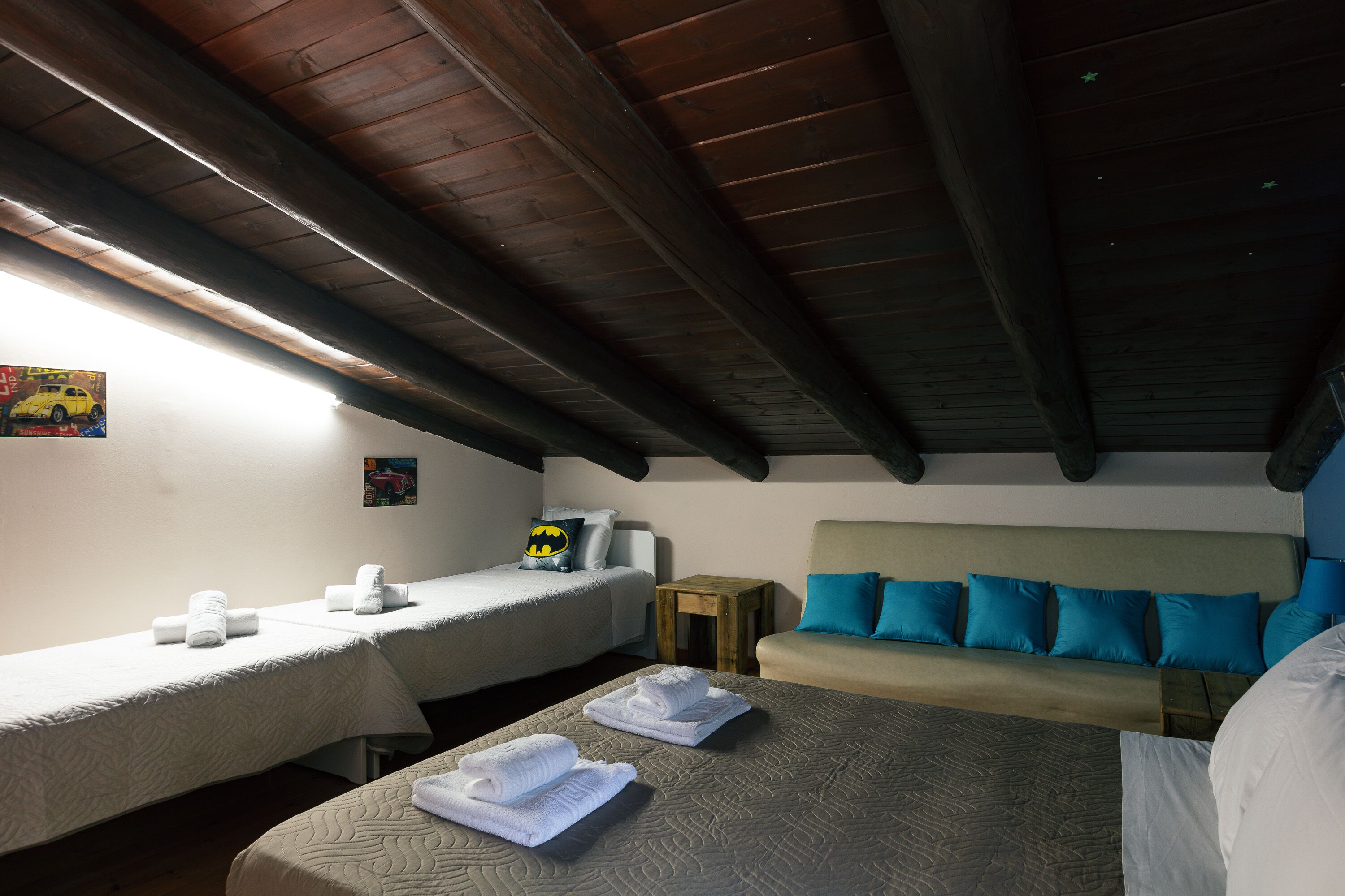 A hotel room with two single beds, a sofa bed, and a small wooden table.
