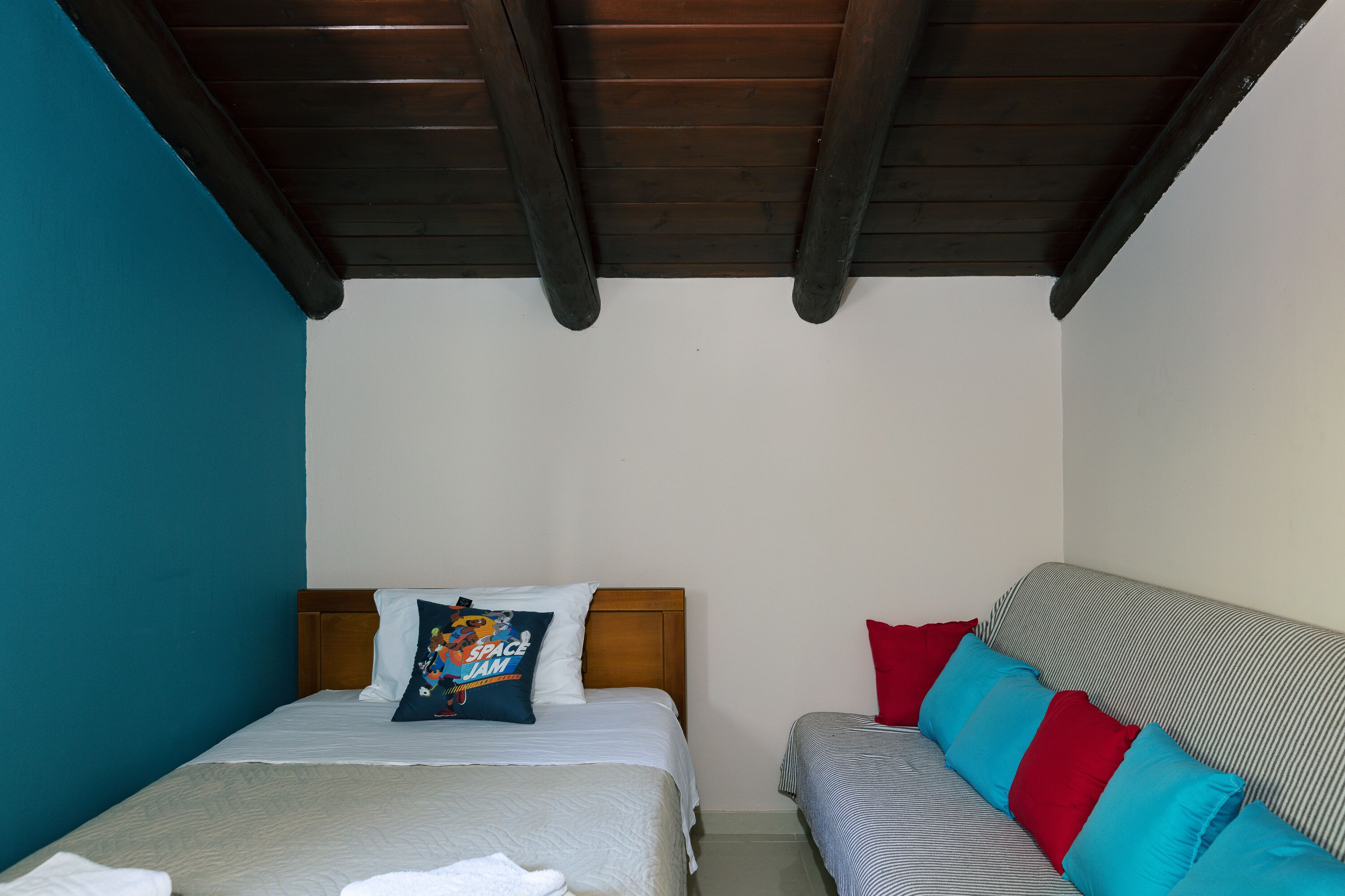Ein Schlafzimmer mit einem Bett, einer Couch und einer Holzbalkendecke.