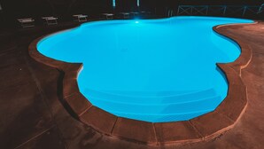 Una piscina de borde curvo, rodeada por un deck de color oscuro.