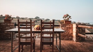 Una mesa y sillas de madera en un patio de piedra con vistas a un paisaje montañoso.