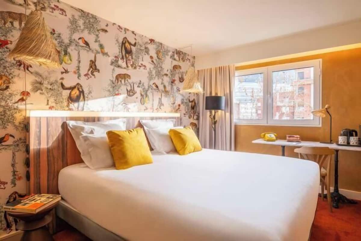 Een hotelkamer met een bed, een bureau, een stoel, een lamp en een raam.