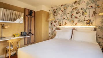 Quarto de hotel com cama, escrivaninha e cadeira, espelho e painel decorado com motivos da natureza.