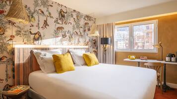 Une chambre d’hôtel avec un grand lit, un bureau avec une lampe et une fenêtre avec des rideaux.