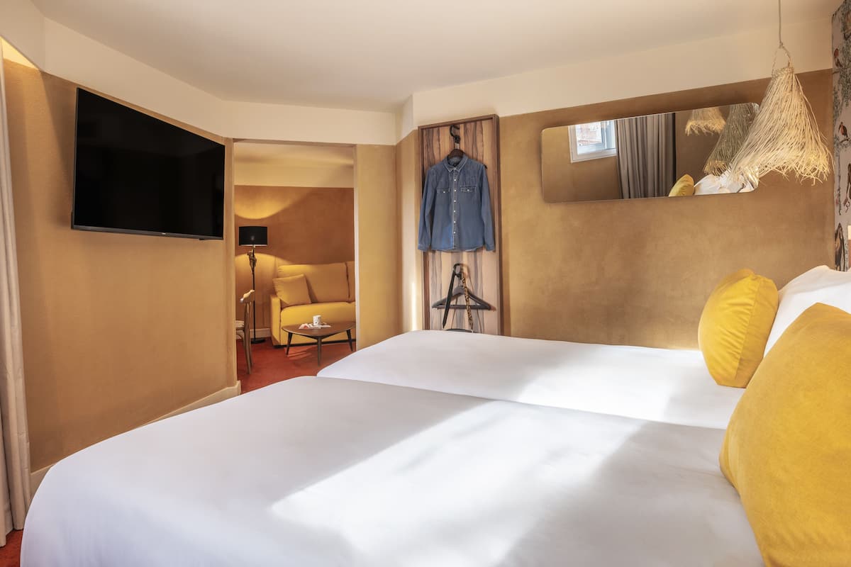 Een hotelkamer met een groot bed, een aan de muur bevestigde televisie, een stoel en een klein tafeltje.