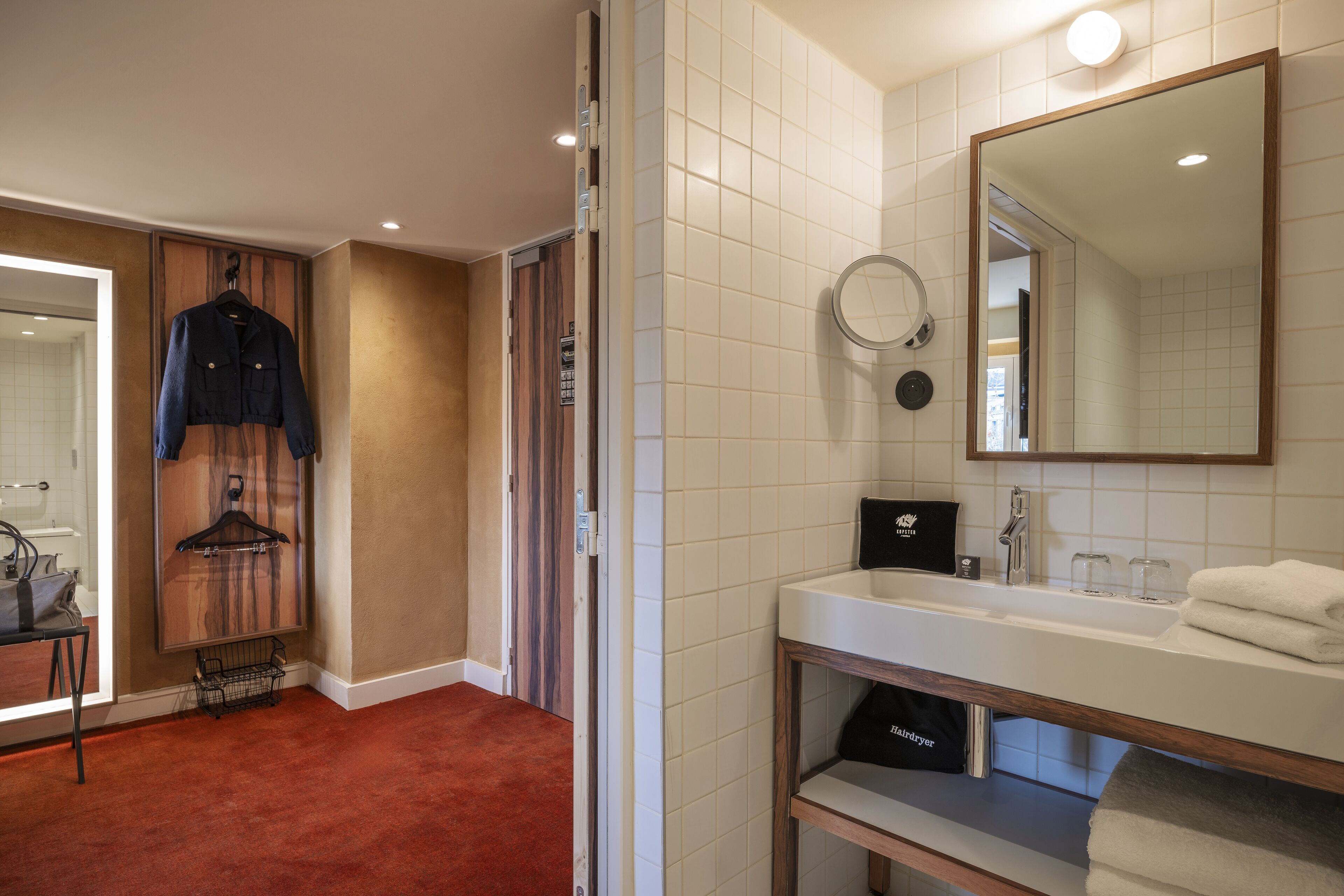 A hotel bathroom with a white sink, mirror, and towel rack.