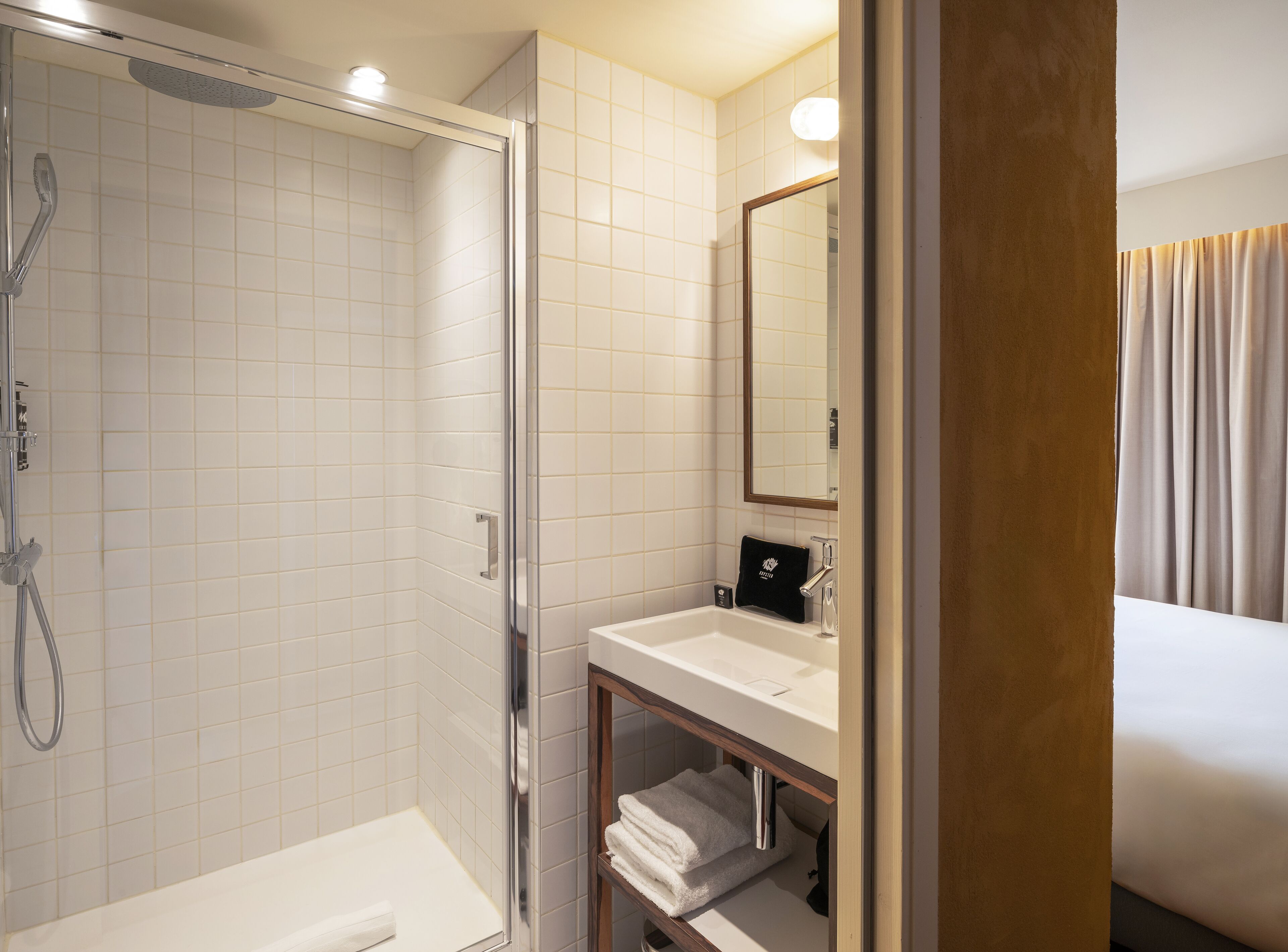 A modern bathroom with a glass-enclosed shower, a white sink, and a mirror above it.