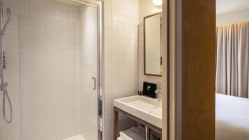 A modern bathroom with a glass-enclosed shower, a white sink, and a mirror above it.