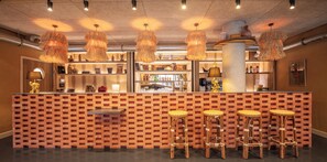 Un espace bar avec un mur en briques, des luminaires suspendus et des tabourets de bar.