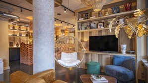Un salon moderne avec un fauteuil suspendu, un canapé, une télévision et une bibliothèque.