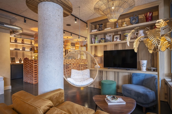 A modern living room with a hanging chair, a sofa, a television, and a bookshelf.