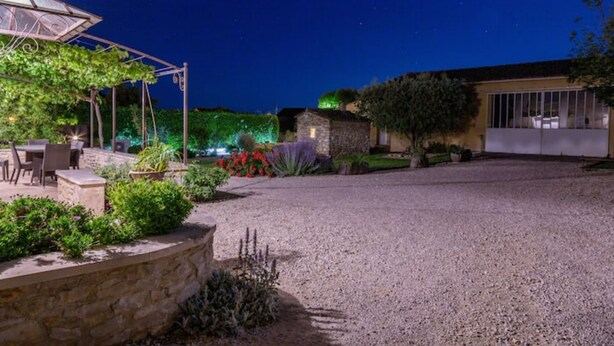A gravel driveway leading to a stone building with a covered patio area. - L'Oustau de Famiho Air-conditioned gite with pool in renovated farmhouse 10 km from Avignon (Châteauneuf-de-Gadagne)