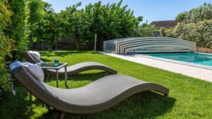 A poolside area with two lounge chairs, a small table with a drink, and a modern pool structure. - L'Oustau de Famiho Air-conditioned gite with pool in renovated farmhouse 10 km from Avignon (Châteauneuf-de-Gadagne)