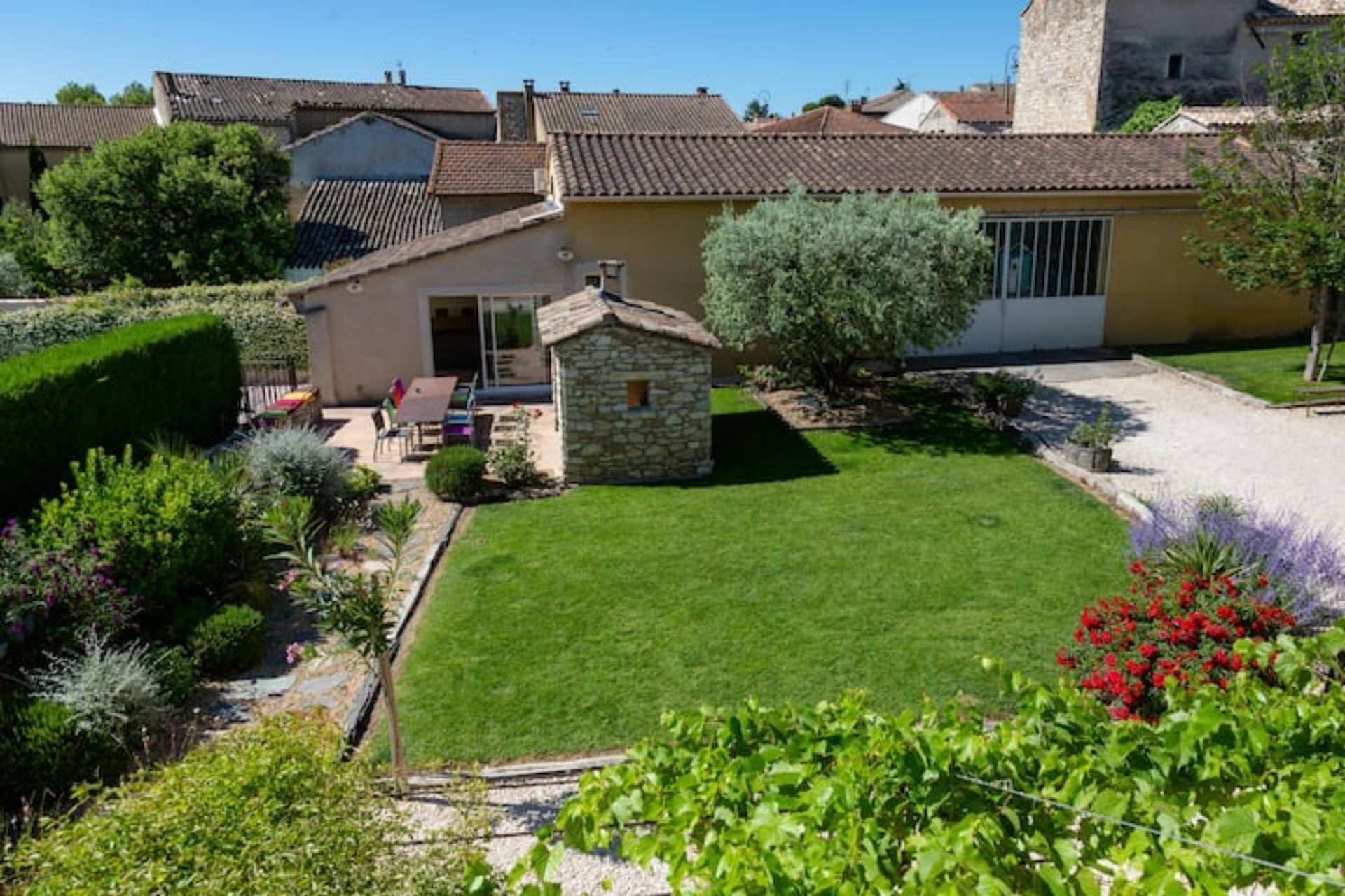 Una propiedad residencial con un césped cuidado, una estructura de piedra y una casa con techo de tejas.