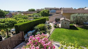 A residential area with a well-maintained garden, a stone structure, and a house with a tiled roof. - L'Oustau de Famiho Air-conditioned gite with pool in renovated farmhouse 10 km from Avignon (Châteauneuf-de-Gadagne)