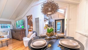 Un comedor con una mesa redonda dispuesta para cuatro personas, una chimenea y un televisor al fondo.