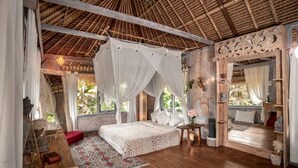 Ein geräumiges Schlafzimmer mit Baldachinbett, Holzboden und einem Strohdach.