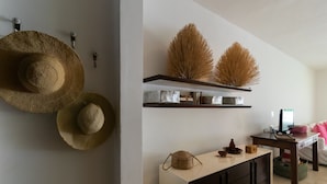 A room with a wall-mounted shelf holding decorative items, a cabinet with a woven basket, and a television on a desk. - NEW LISTING! PRIVATE POOL CONDO ON 5TH AVE, BBQ, PARKING, 2min walk to beach (Playa del Carmen)