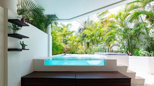 A modern outdoor pool area with a built-in hot tub, surrounded by lush tropical plants. - NEW LISTING! PRIVATE POOL CONDO ON 5TH AVE, BBQ, PARKING, 2min walk to beach (Playa del Carmen)
