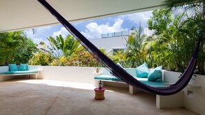 A hammock chair with cushions, a small round table with a drink, and a view of a cityscape through a glass ceiling. - NEW LISTING! PRIVATE POOL CONDO ON 5TH AVE, BBQ, PARKING, 2min walk to beach (Playa del Carmen)