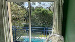 A room with a bed, a table, and a chair. There is a sliding glass door leading to a pool area. - House with private pool near the sea (Lanton)