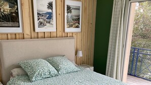 A bedroom with a bed, a nightstand, a lamp, and framed pictures on the wall. - House with private pool near the sea (Lanton)